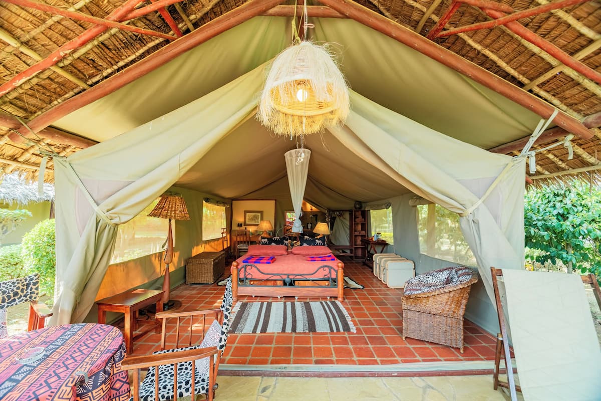 Eine Zelthütte mit Bett, Sitzgelegenheit und einer Hängelampe.