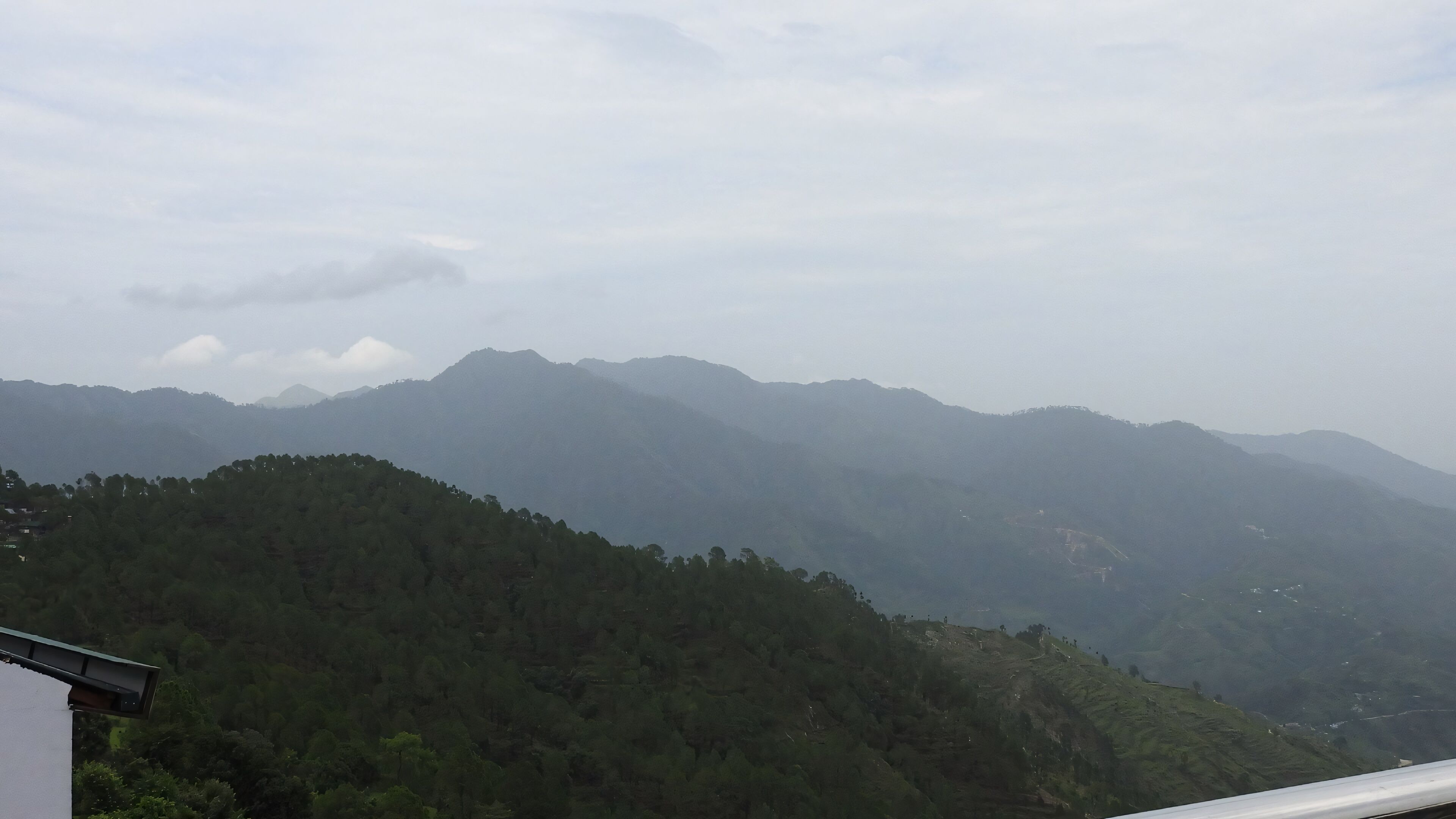 A mountainous landscape with dense forested hills and a clear sky.