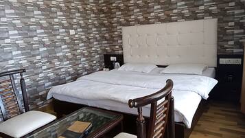 A modern hotel room with a stone-patterned wall, a tufted headboard, a glass coffee table, and a wooden chair.