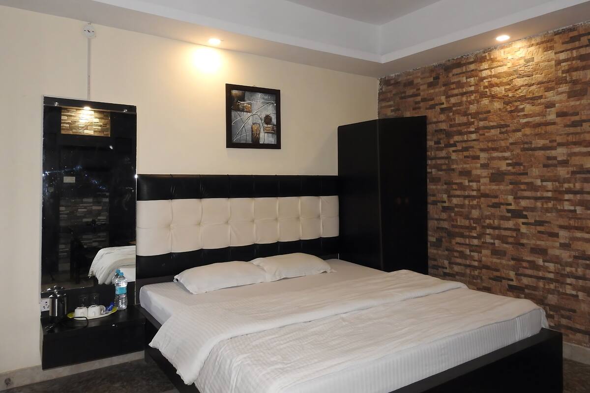 A modern bedroom with a large bed, a black wardrobe, a mirror, and a wall-mounted clock.