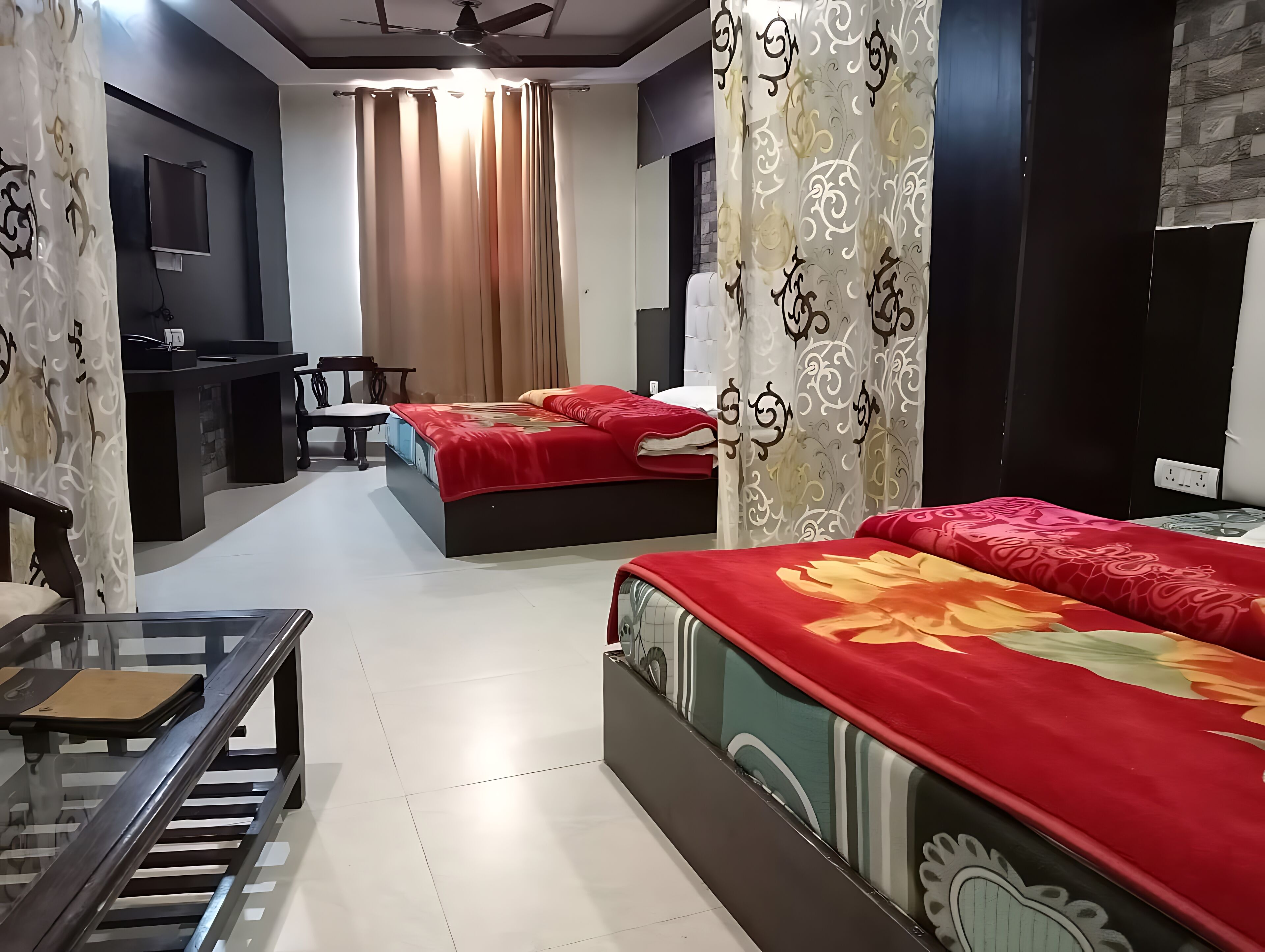 A hotel room with two beds, a desk, a chair, and a small table.