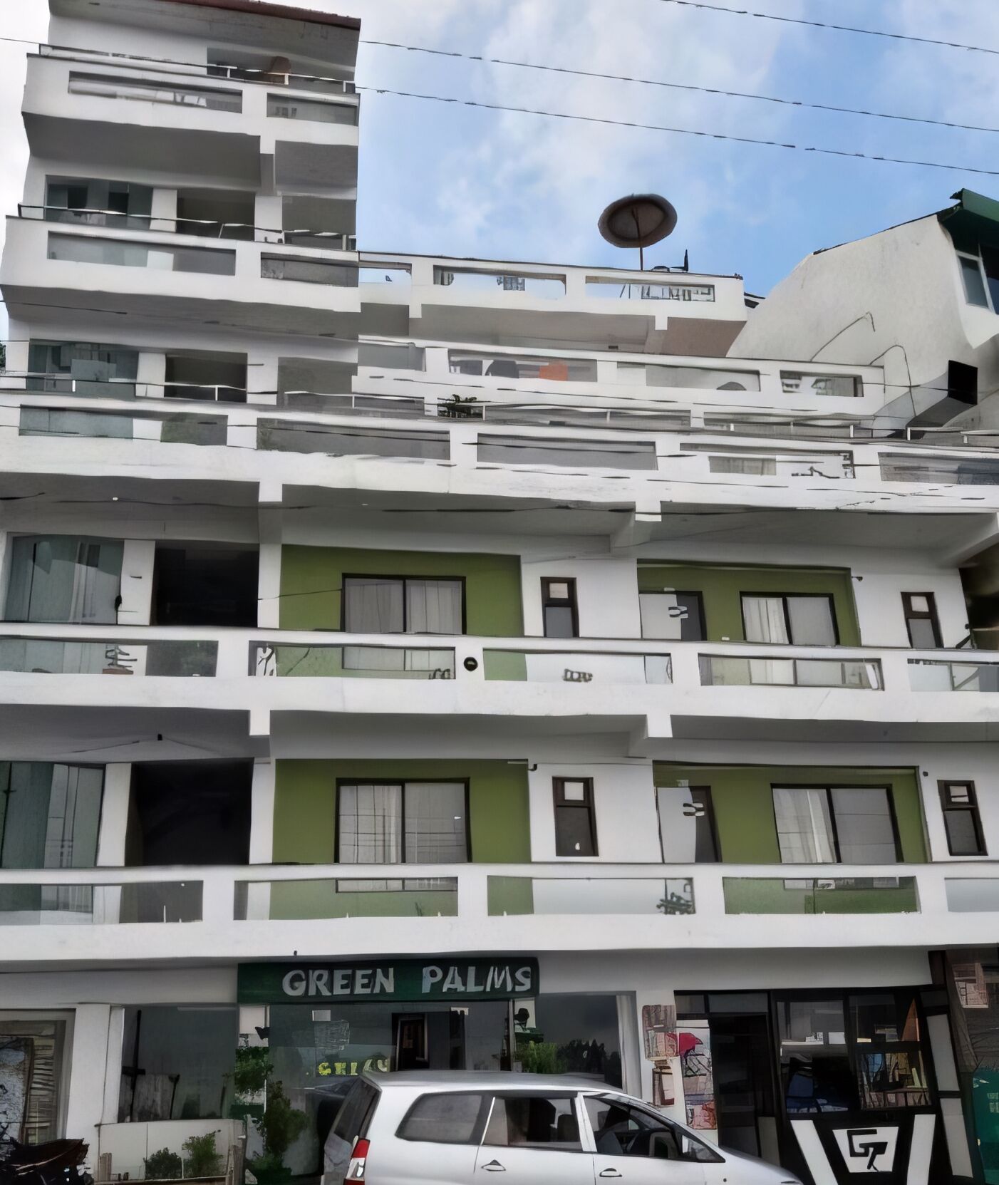 A multi-story building with a green storefront labeled "GREEN PALMS".