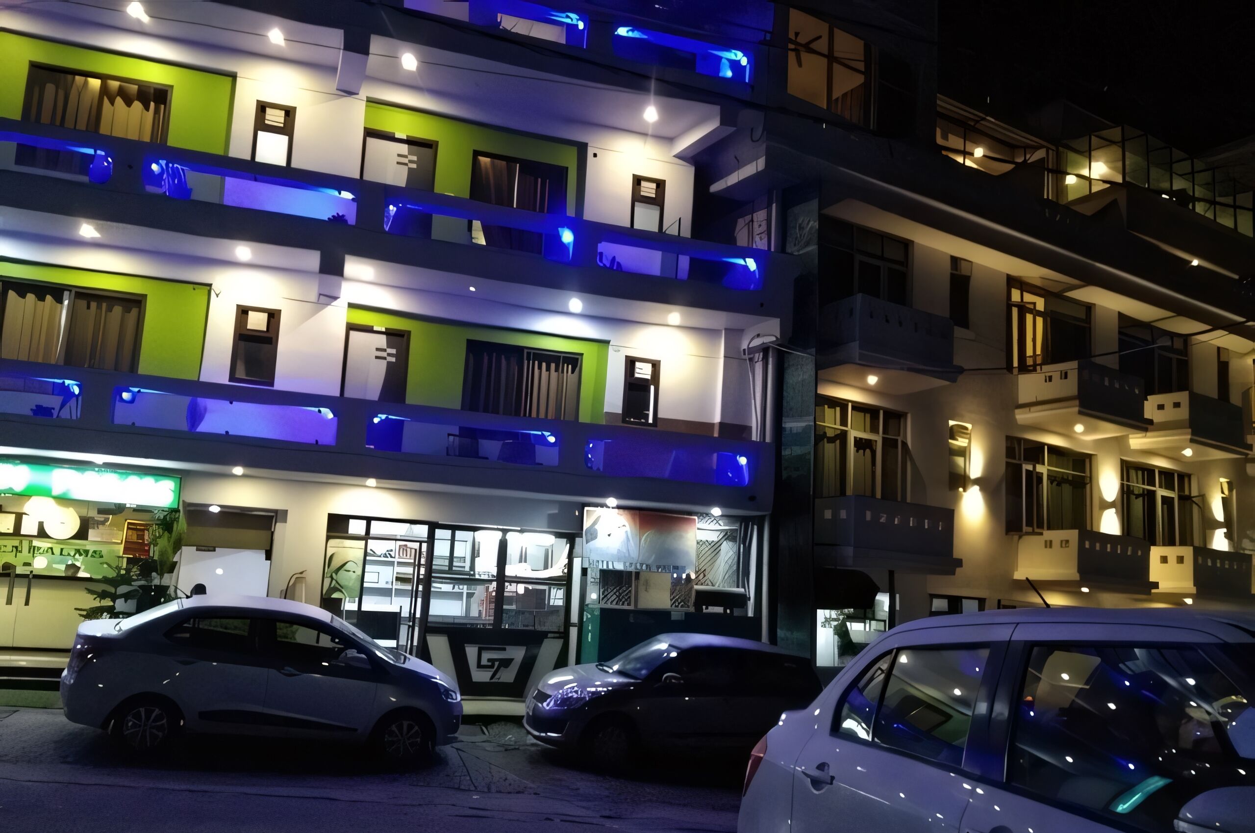 A multi-story hotel with balconies, a restaurant at the ground level, and cars parked in front.
