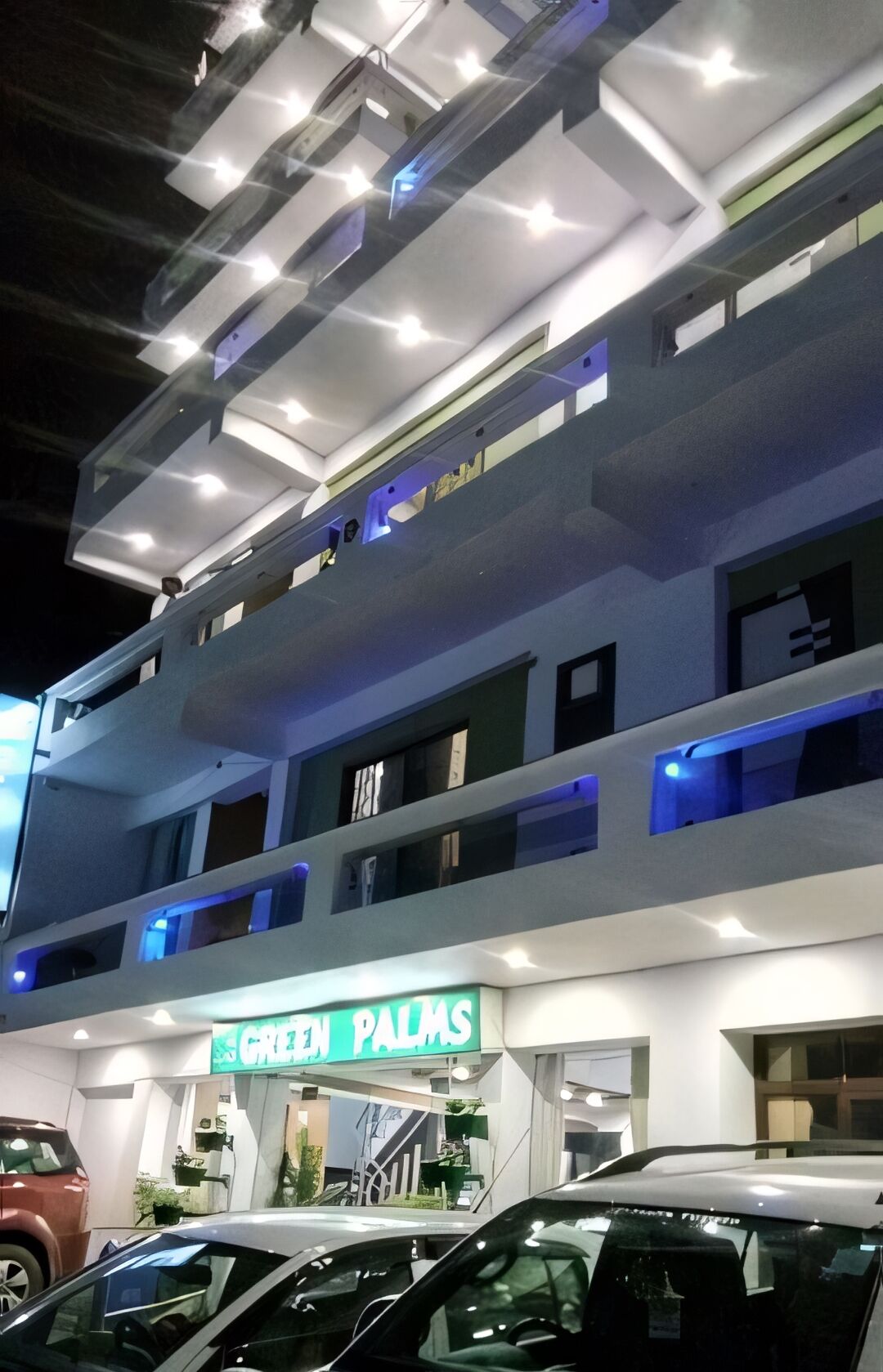 A multi-story building with a sign reading "GREEN PALMS".