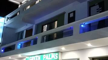 A multi-story building with a sign reading "GREEN PALMS".