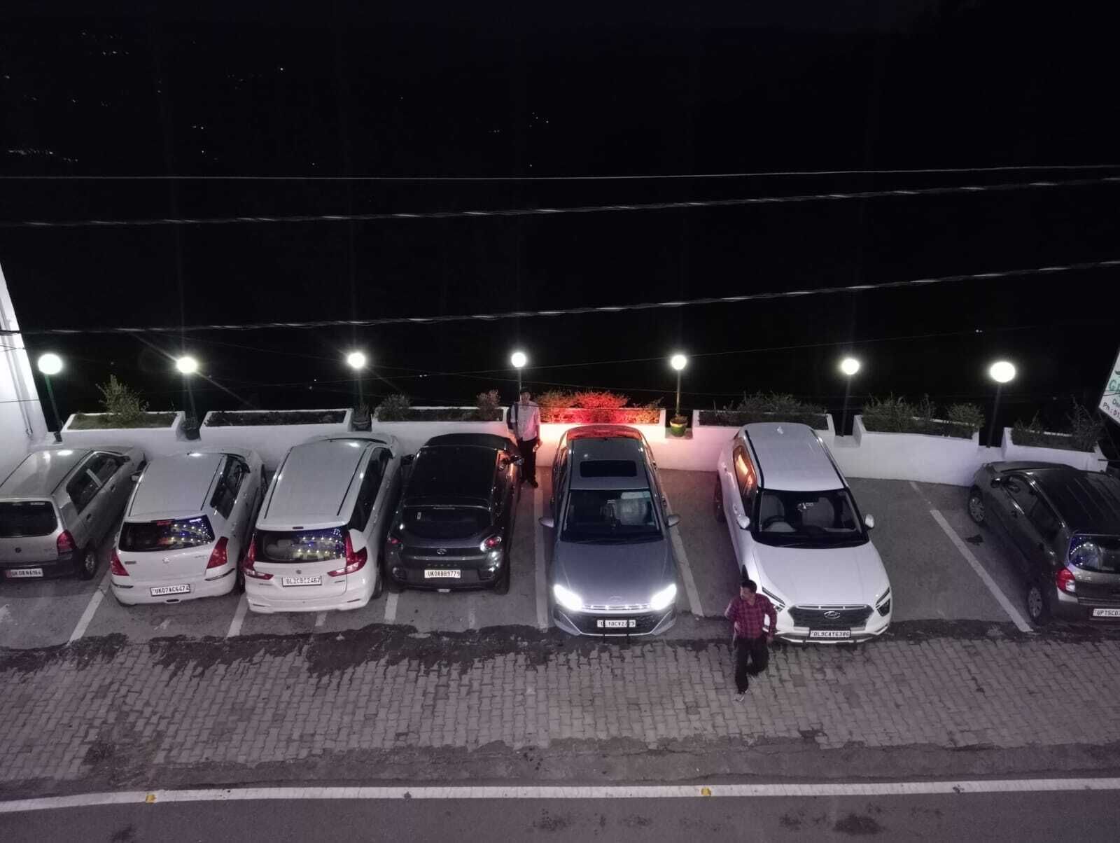 A parking lot at night with several cars parked in rows, illuminated by overhead lights.