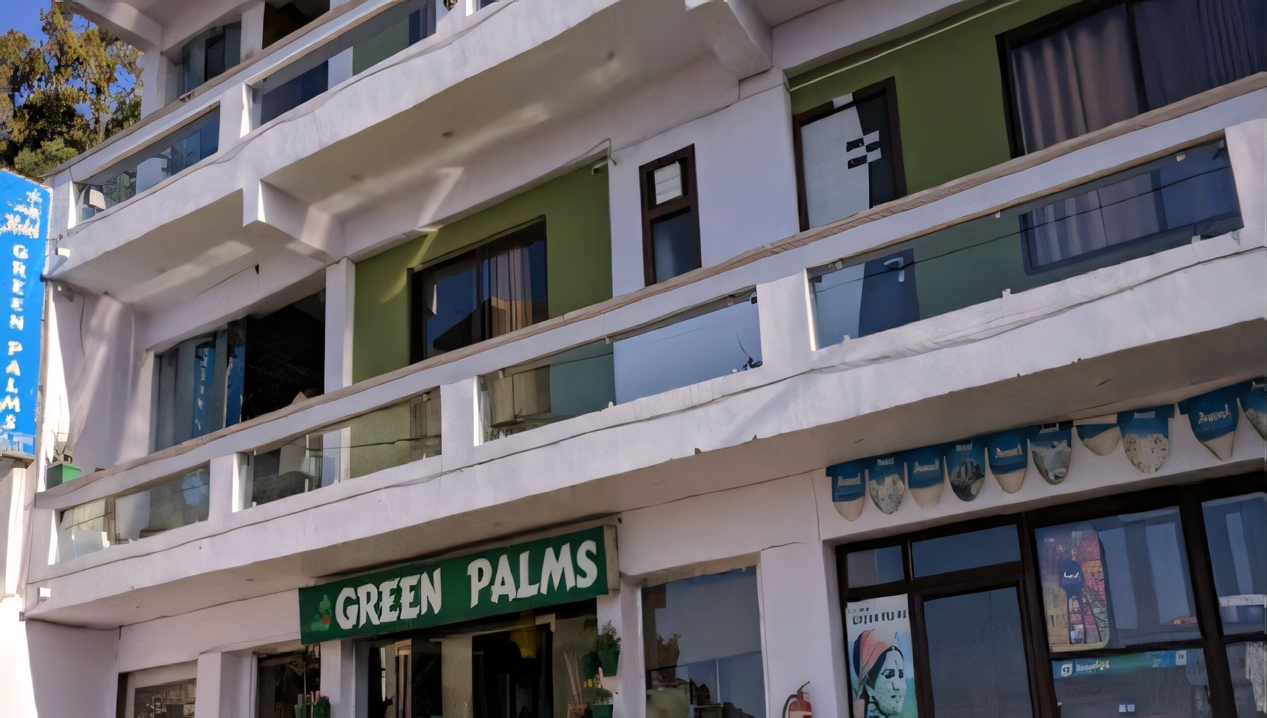 Un edificio de varios pisos con un letrero verde que dice "GREEN PALMS".
