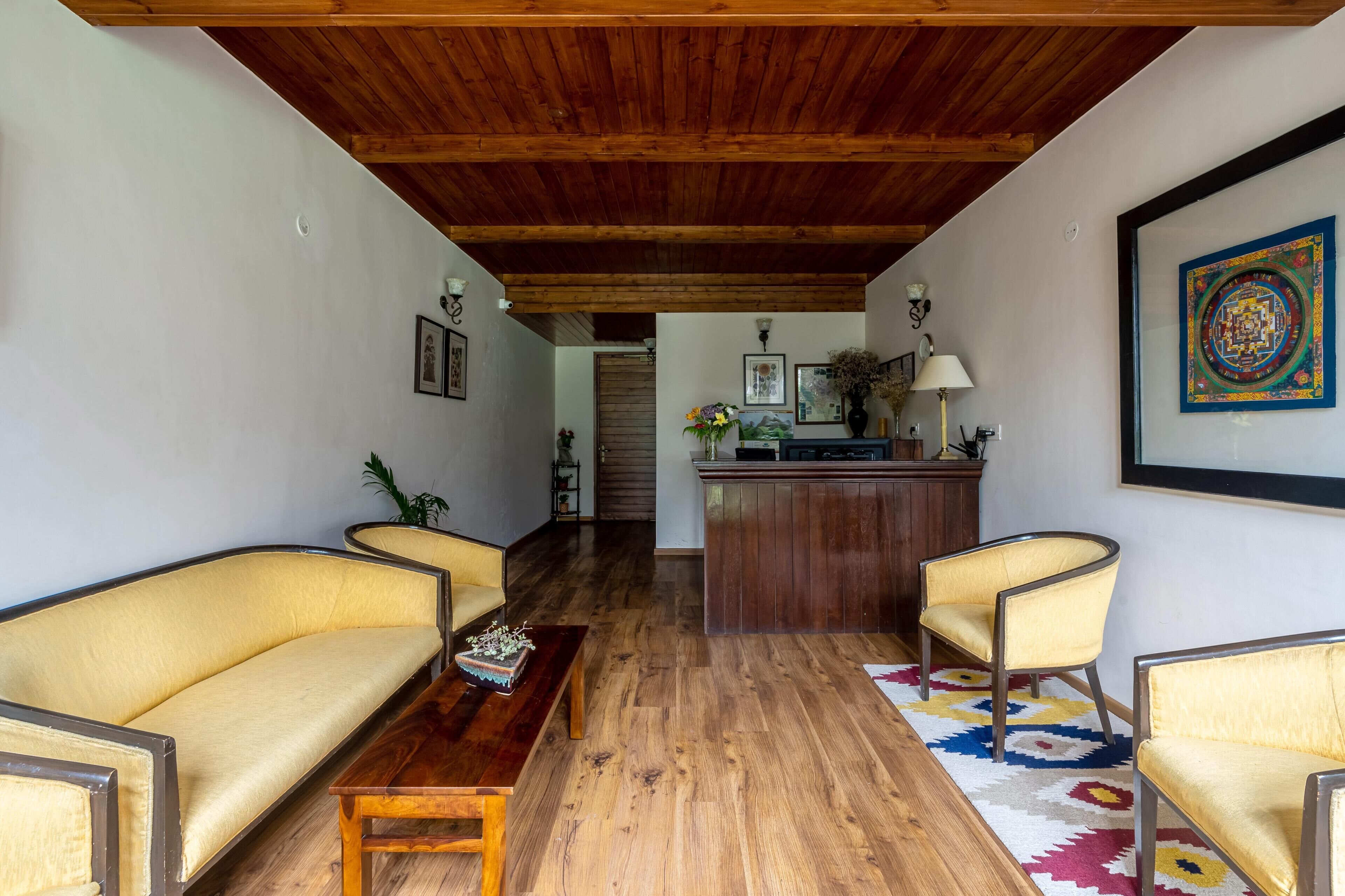 A living room with wooden flooring, a sofa, a coffee table, and a patterned rug.