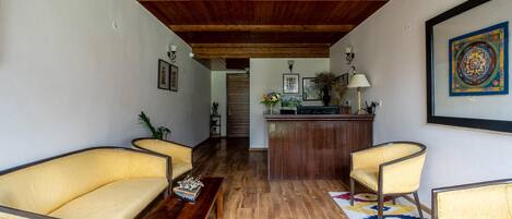 A living room with wooden flooring, a sofa, a coffee table, and a patterned rug.