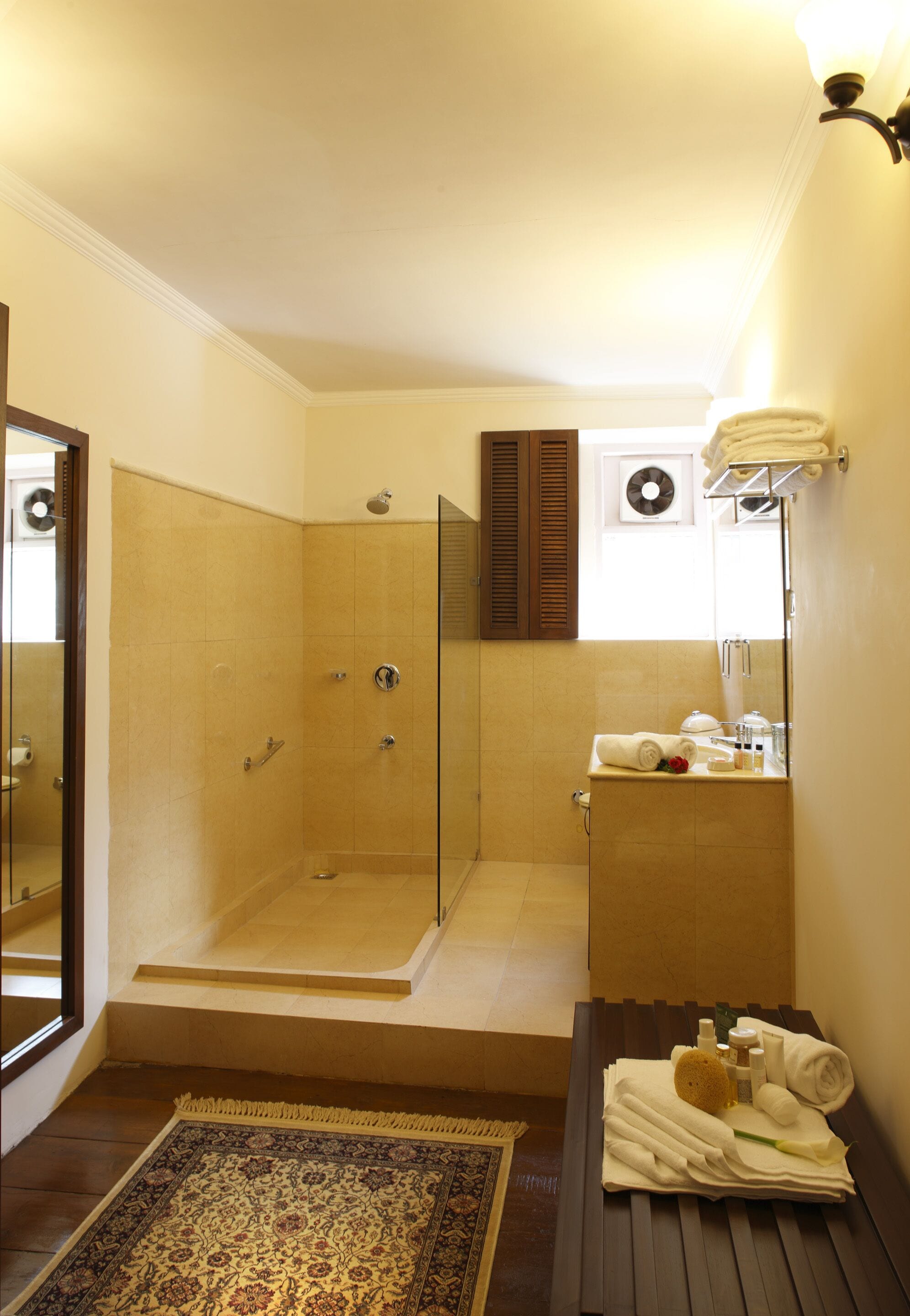 A bathroom with a glass-enclosed shower, a sink with toiletries, and a mirror.