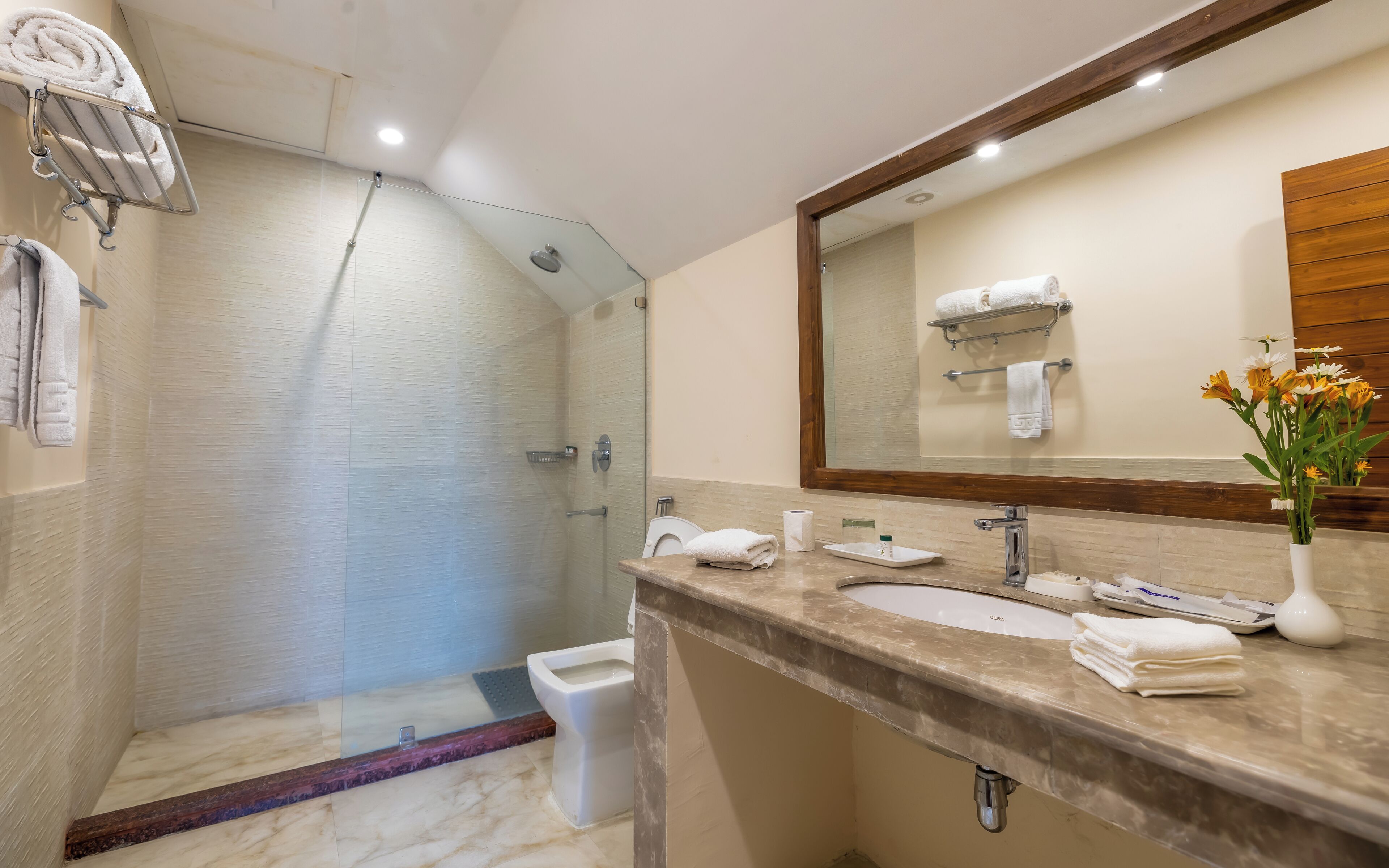 A modern bathroom with a glass-enclosed shower, a marble vanity, and a large mirror.