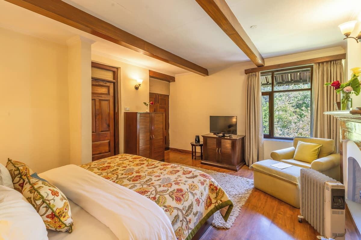 Un dormitorio con cama, televisor, radiador y ventana con cortinas.