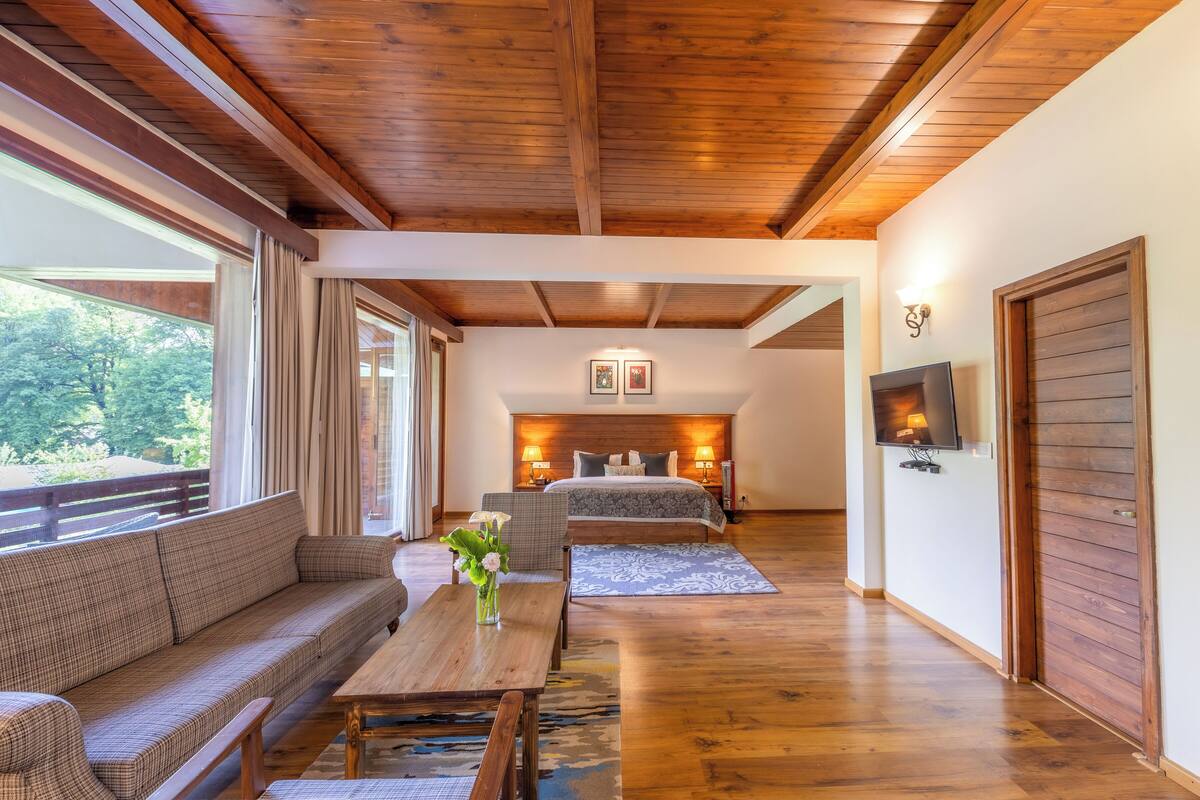 Una habitación amplia con techo de madera, una cama grande, un sofá y un televisor.