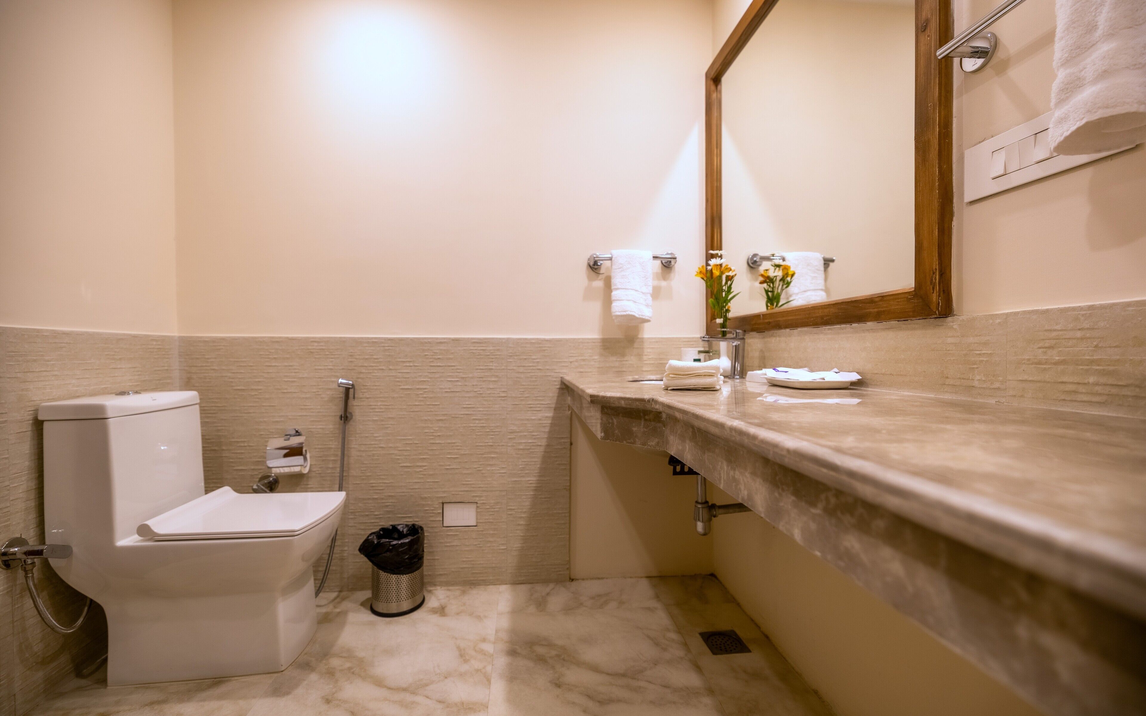 A bathroom with a toilet, bidet, sink, mirror, and towel rack.
