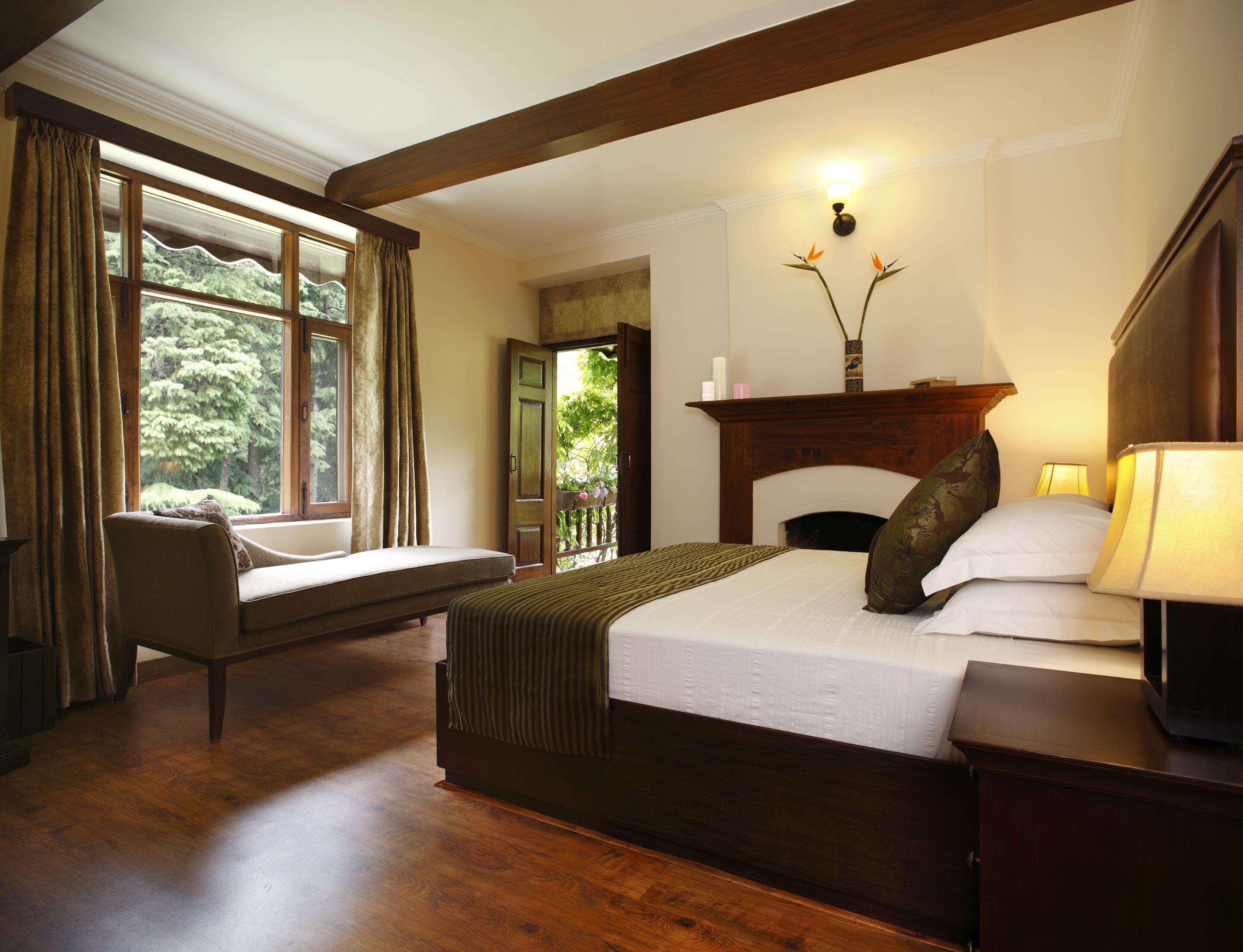 A bedroom with a large bed, a chair, a fireplace, and a window with curtains.