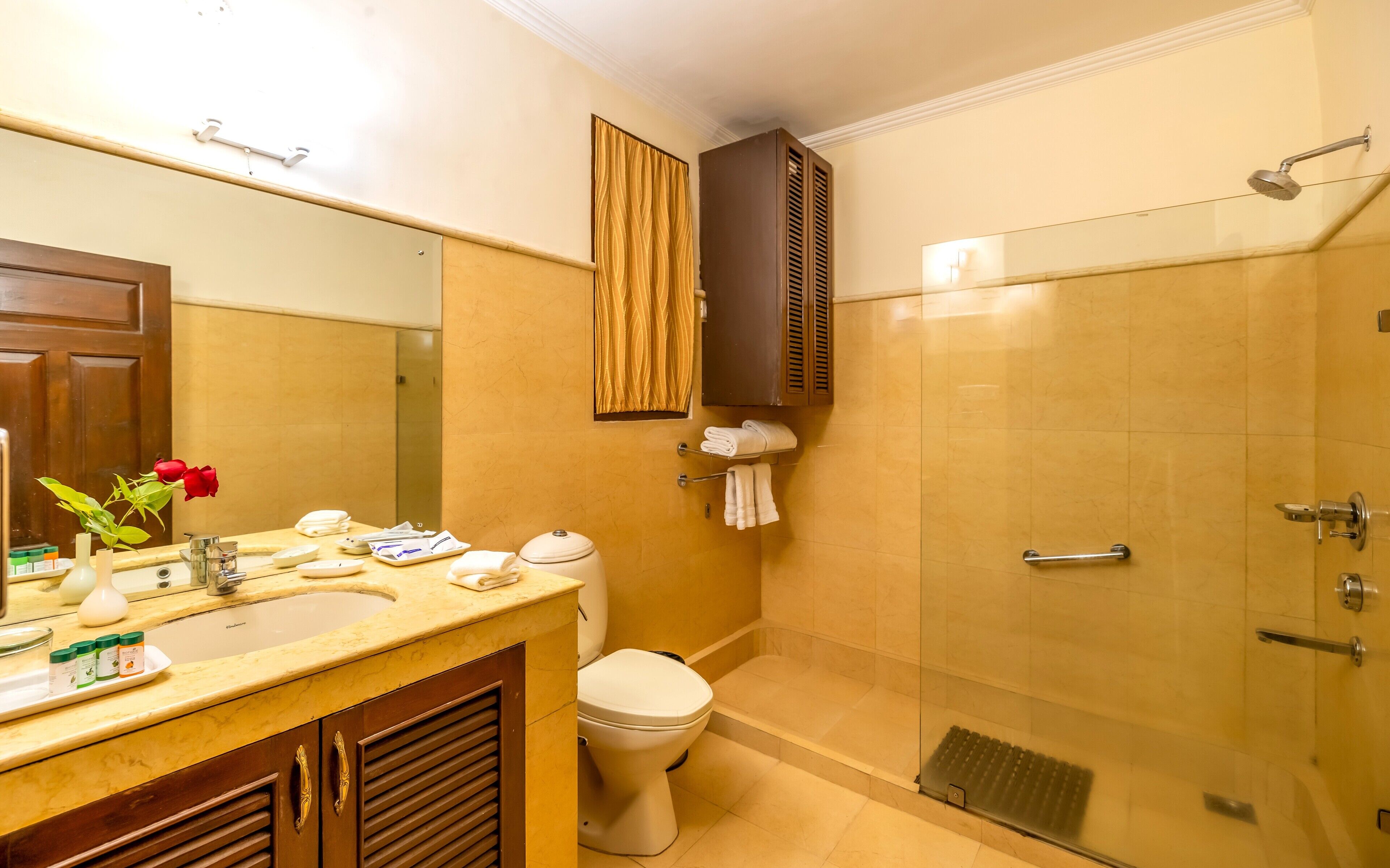 A bathroom with a sink, toilet, and a glass-enclosed shower stall.