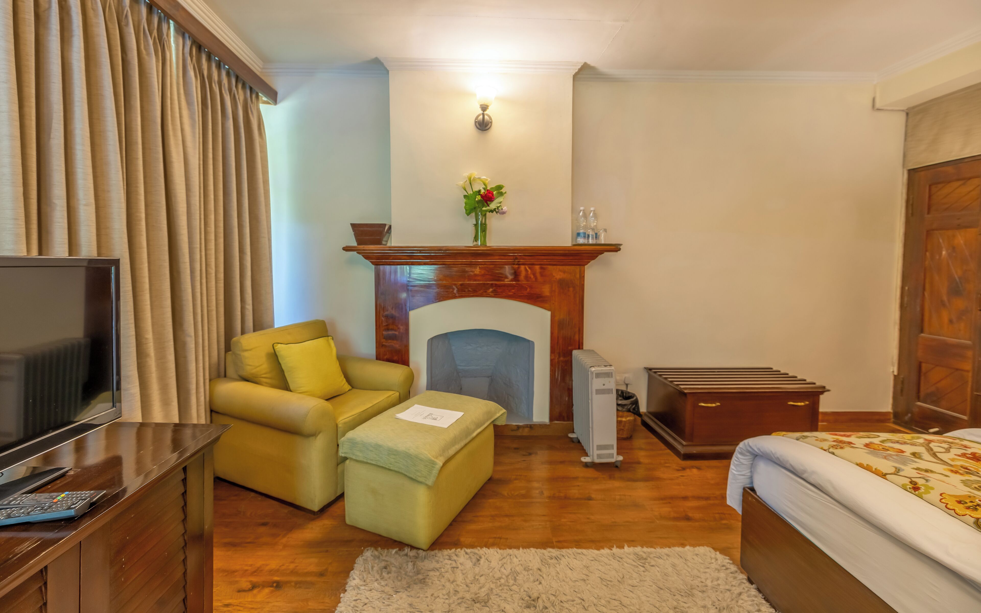 A cozy room with a fireplace, a sofa, a bed, a TV, and a small table.