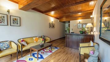 Una sala de estar acogedora con techo de madera, un sofá amarillo, una mesa de centro y una mesita auxiliar con lámpara.
