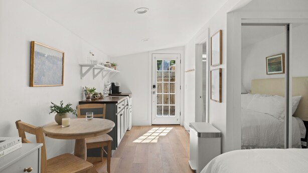A compact room with a bed, a small dining area, and a kitchenette. - Charming Downtown Country Cottage (Chico)