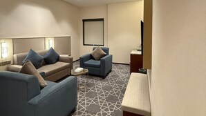 Moderni hotellihuone, jossa on sohvaryhmä, pieni pöytä ja televisio.
