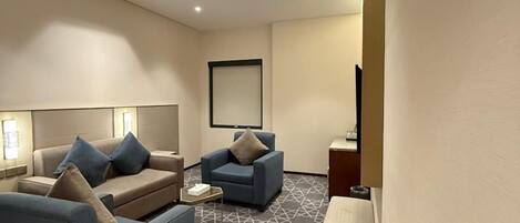 Una habitación de hotel moderna con un conjunto de sofás, una mesita y un televisor.