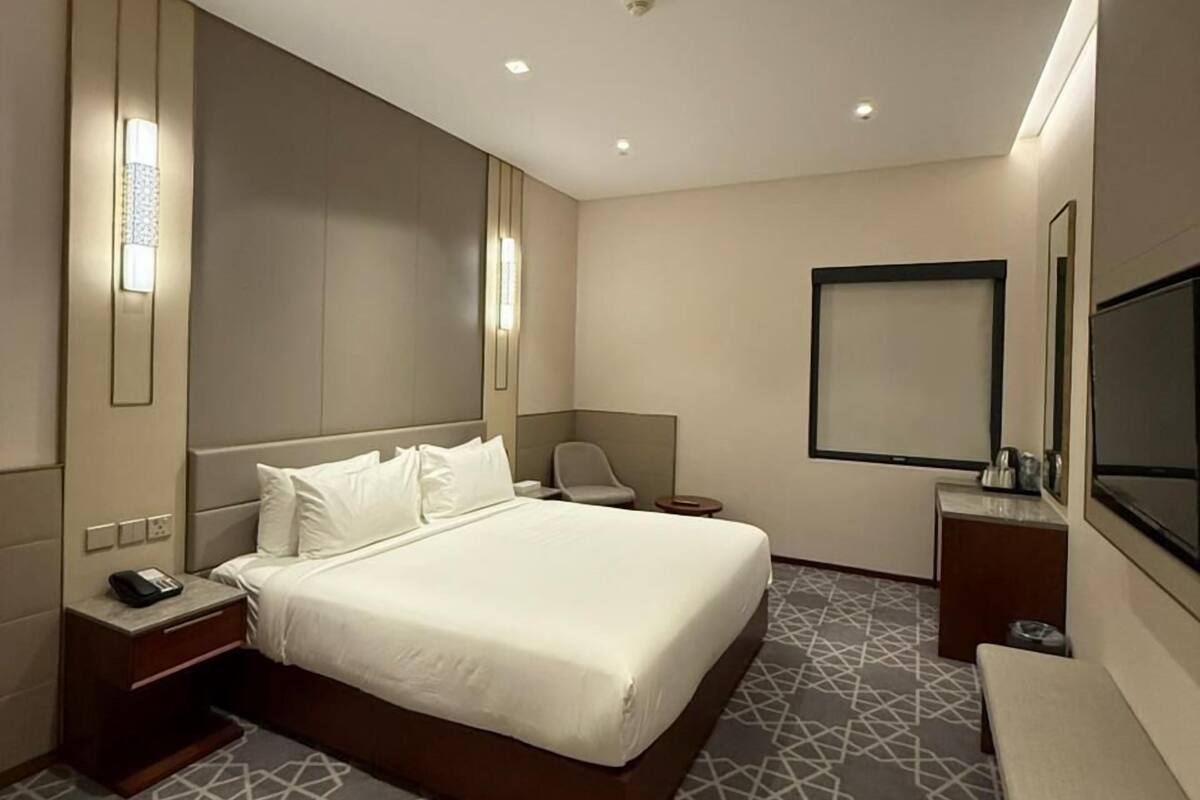 Ein modernes Hotelzimmer mit einem großen Bett, Nachttischen, einem Schreibtisch und einem Fernseher.