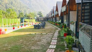 A row of modern bungalows with a paved walkway and outdoor seating area. - Eden Rock River Resort (Rishikesh)