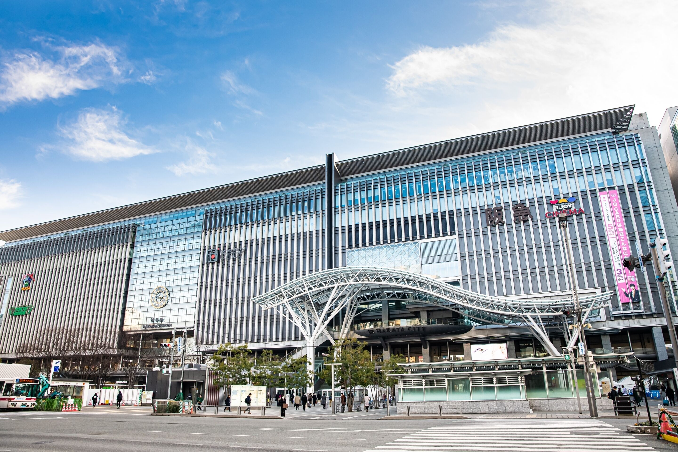 A modern building with a glass facade and a distinctive white canopy structure.
