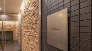 A wall with a textured stone pattern and a sign that reads "VIDA Hakata". - vida hakata (Fukuoka)