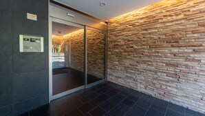 A modern interior with a stone wall, a glass door, and a control panel. - vida hakata (Fukuoka)
