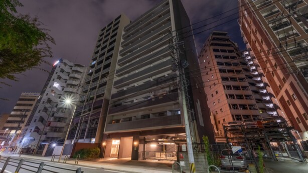 A multi-story building with a modern architectural design, featuring a prominent entrance with glass doors and a covered walkway. - vida hakata (Fukuoka)