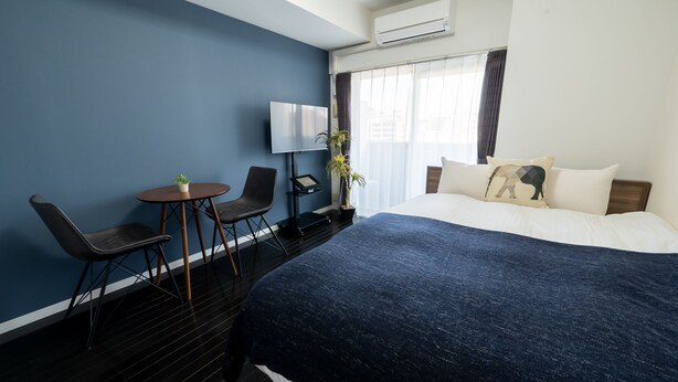 A hotel room with a large bed, a desk with a chair, a TV, and a potted plant. - vida hakata (Fukuoka)