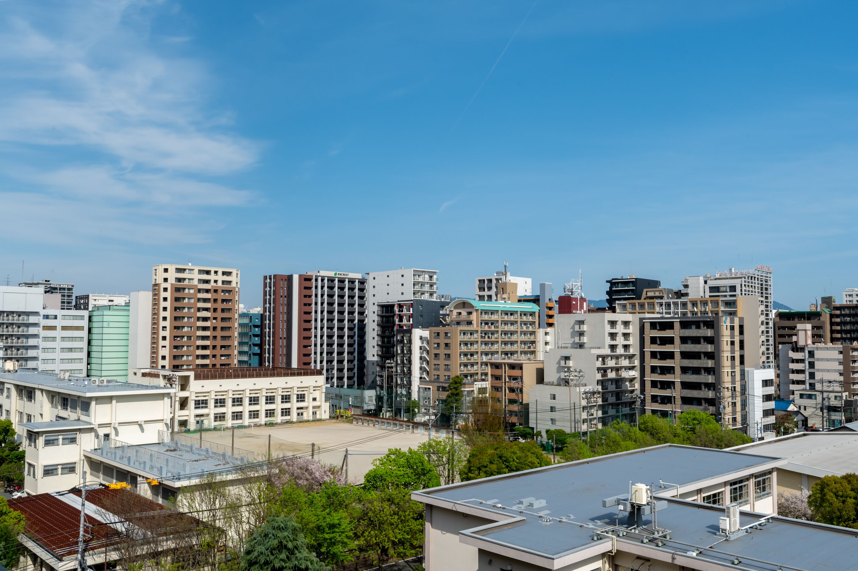 A cityscape with multiple high-rise buildings, some with commercial signs, and a clear blue sky.