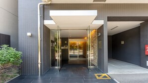 A modern building entrance with glass doors, a tiled floor, and a small plant on the left. - vida hakata (Fukuoka)