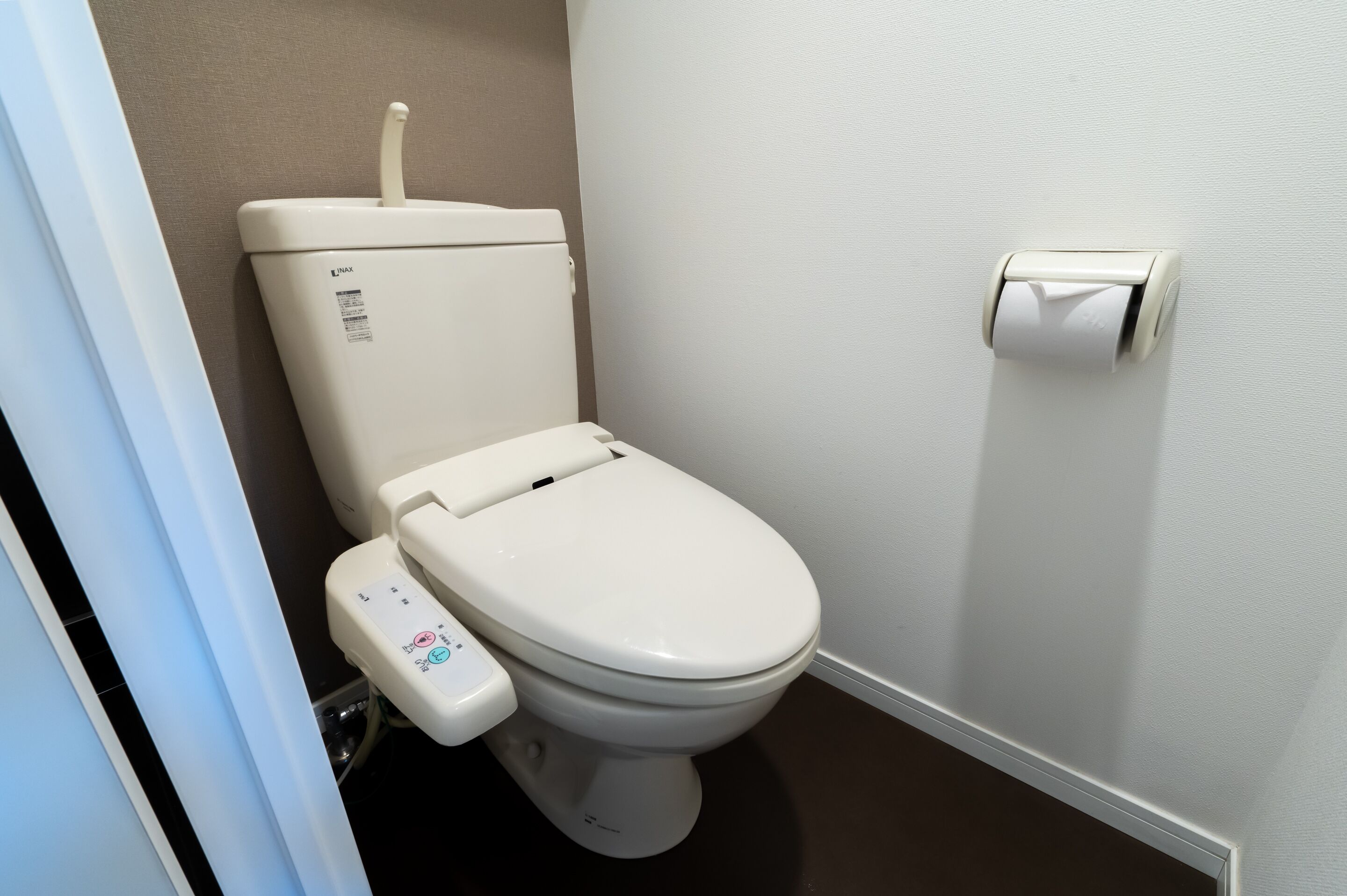 Moderni wc, jossa on ohjauspaneeli, wc-paperiteline ja näkyvissä oleva vesisäiliö.