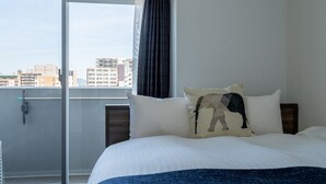 A hotel room with a bed, a view of buildings through a window, and a curtain. - vida hakata (Fukuoka)