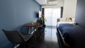 A hotel room with a bed, a TV, a desk with a chair, and a small table with a plant. - vida hakata (Fukuoka)