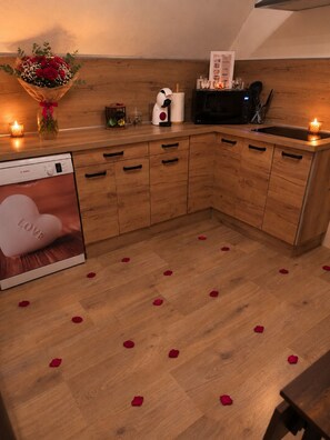 A kitchen with wooden cabinets, a Bosch dishwasher, a coffee machine, and a bouquet of red roses on the counter. - Gîte Maison de Campagne au nid D'ange Avec Jacuzzi (Saint-Michel-l'Observatoire)
