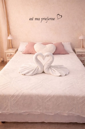 A bed with a heart-shaped towel arrangement and a wall sign that reads 'est ma preferee'. - Gîte Maison de Campagne au nid D'ange Avec Jacuzzi (Saint-Michel-l'Observatoire)