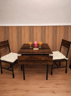 A wooden dining table with two chairs, a pink candle, and two heart-shaped glasses on it. - Gîte Maison de Campagne au nid D'ange Avec Jacuzzi (Saint-Michel-l'Observatoire)