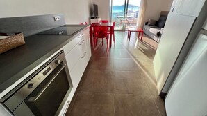 A modern kitchen with a dining area, a sofa, and a view of the sea. - Appartement Sole - Vue Splendide sur le Golfe de Porto-vecchio (Porto-Vecchio)
