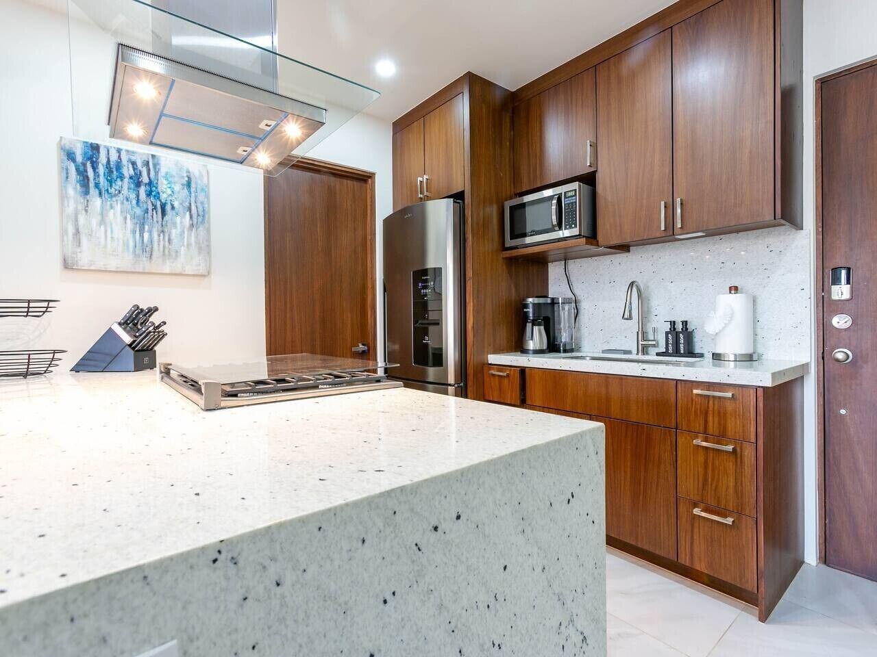 A modern kitchen with wooden cabinets, stainless steel appliances, and a granite countertop.