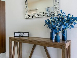 A wooden console table with two framed signs and a vase with blue foliage. - This brand-new 2-bedroom, 2-bath condo offers modern comfort with a stylish open layout and fully equipped kitchen. Enjoy a private rooftop terrace with outdoor kitchen and panoramic views—perfect for relaxing and taking in the beauty of Vista Mare. (Cabo San Lucas)