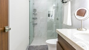 A modern bathroom with a glass shower enclosure, a toilet, a sink with a vanity, and a mirror. - This brand-new 2-bedroom, 2-bath condo offers modern comfort with a stylish open layout and fully equipped kitchen. Enjoy a private rooftop terrace with outdoor kitchen and panoramic views—perfect for relaxing and taking in the beauty of Vista Mare. (Cabo San Lucas)