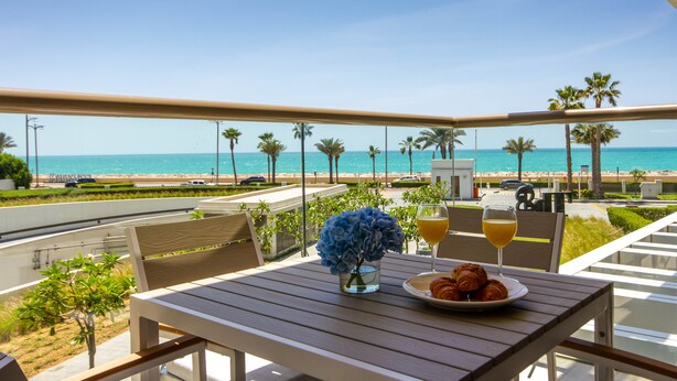 A balcony with a table set for breakfast, overlooking a beach with palm trees and a clear sky. - Bespoke Residences - Th8 Palm Jumeirah (Dubai)