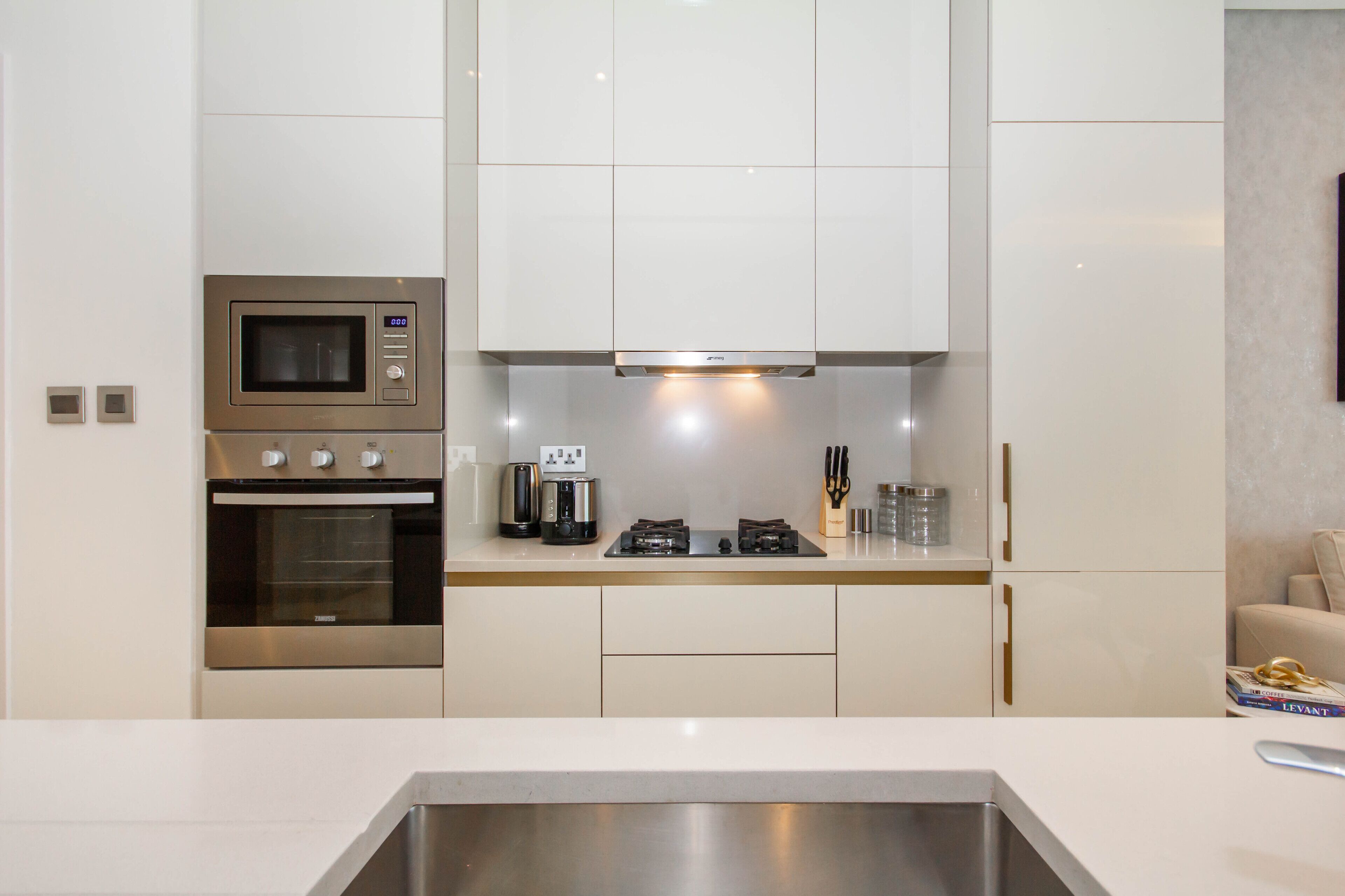 A modern kitchen with stainless steel appliances, including a microwave, oven, and coffee maker, and white cabinetry.