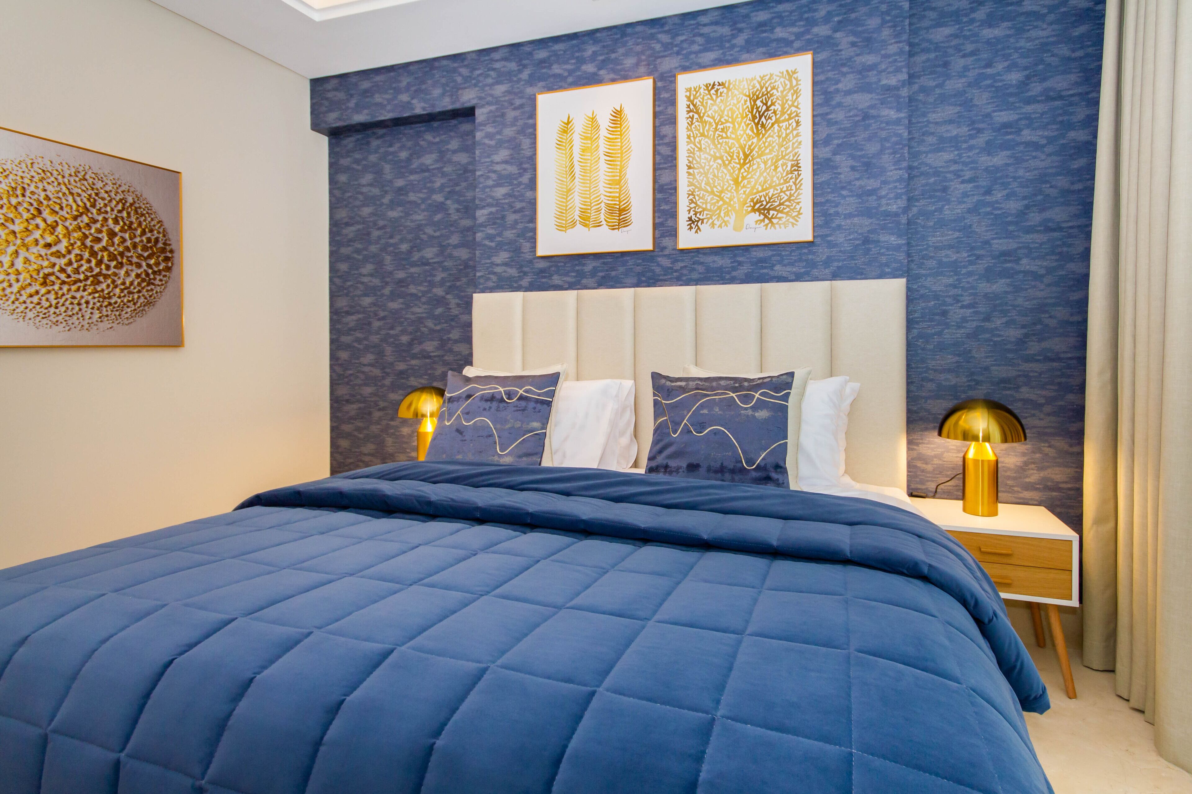 A bedroom with a large bed, two bedside tables with lamps, and artwork on the wall.