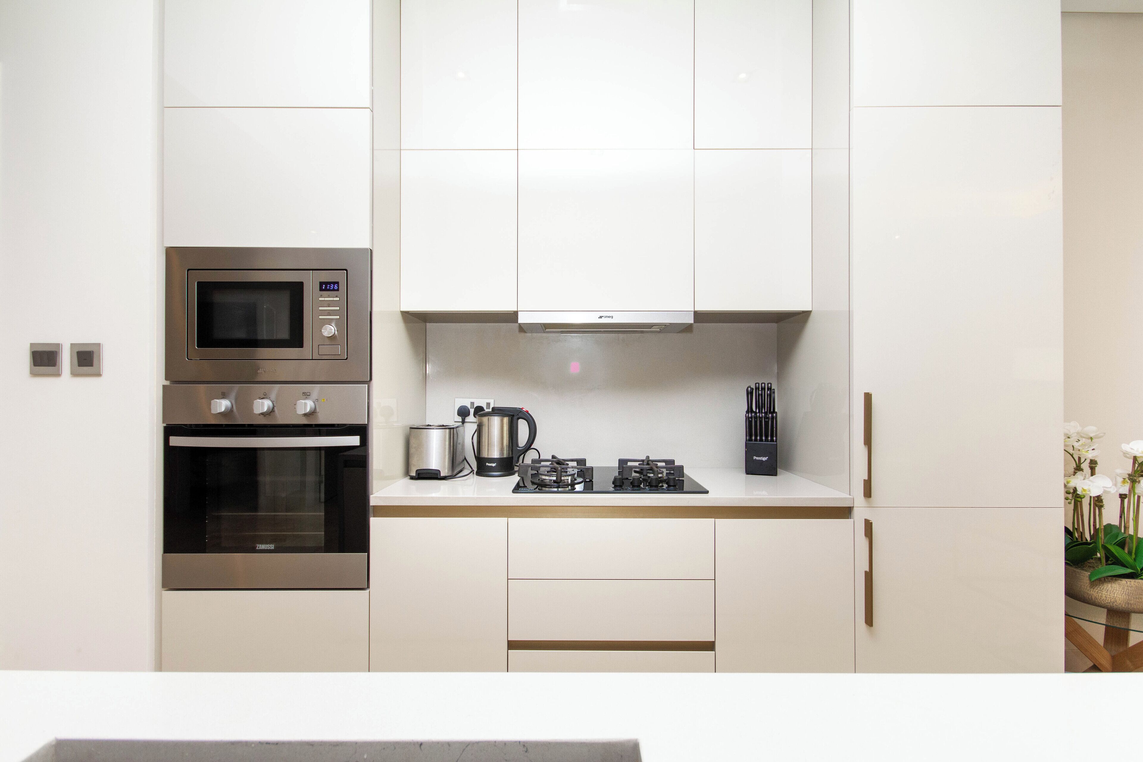 Una cocina moderna con electrodomésticos de acero inoxidable, armarios blancos y una cafetera.