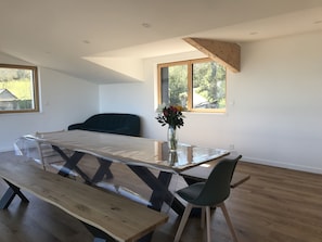 Een moderne eetruimte met een tafel met glazen blad, houten banken en een enkele stoel.