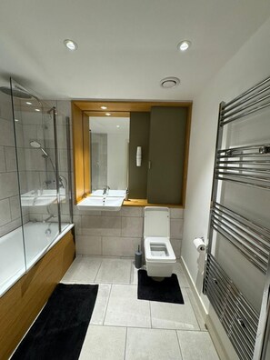 A compact bathroom with a glass-enclosed shower, a toilet, and a sink.